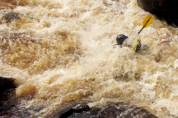Packraft almost totally obscured by whitewater
