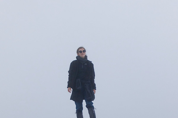Walker standing on top of a rock, in bad weather