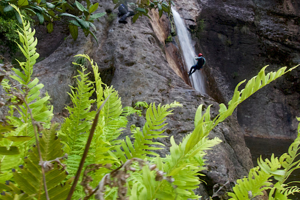 Person in the distance abseiling down a waterfall