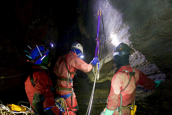 Several cavers at the bottom of a sheer wall