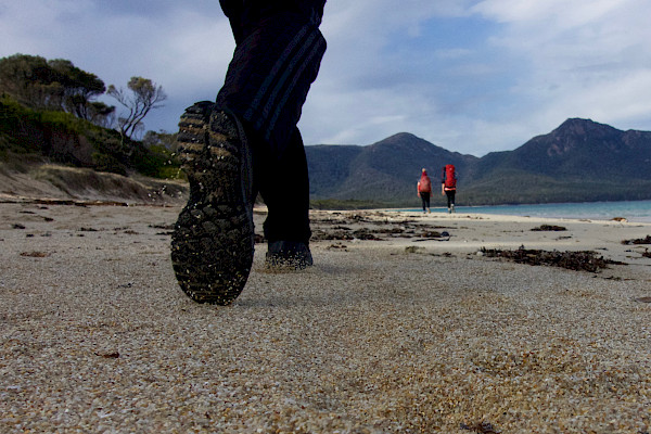 Close-up of feet, walking along a beach