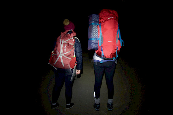 Two people walking along in the dark