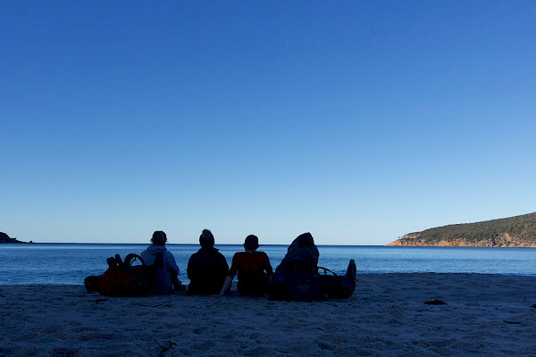 Four people sitting on a beach