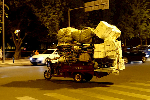 A small vehicle loaded with a huge number of boxes and bags