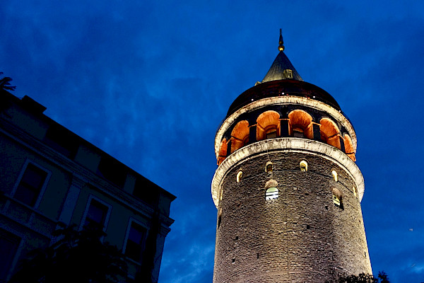 A lit-up stone tower with the evening sky behind